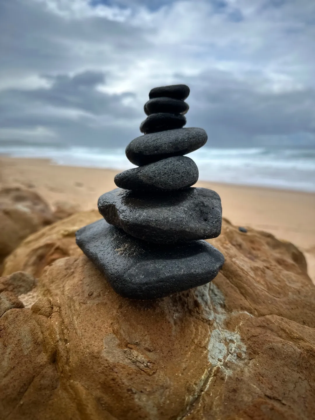 Balanced stone stack on a beach, symbolising equilibrium and focus