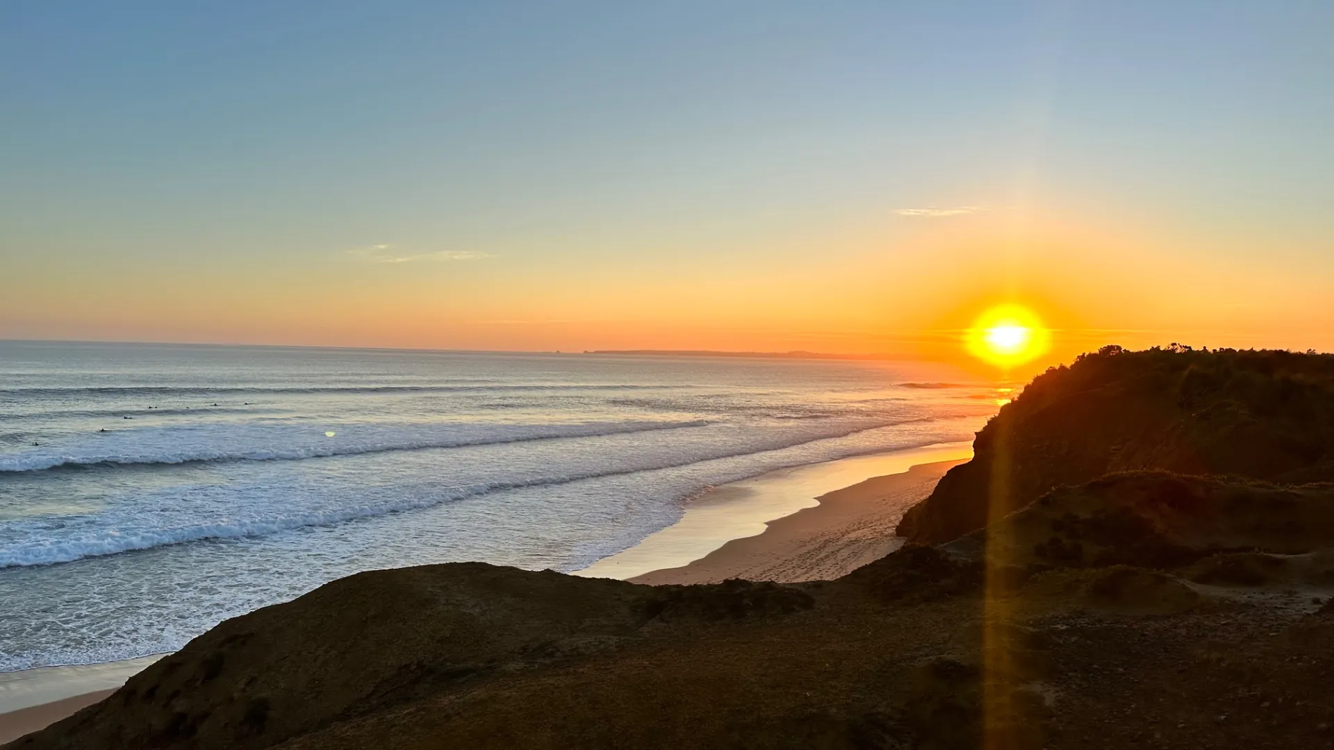 Sunset over a coastline with golden light on breaking waves